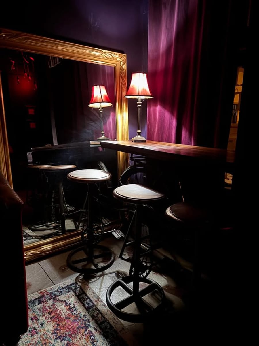 The cozy speakeasy corner at Dark Horse Brew — velvet curtains, a gilded mirror, and warm lamplight