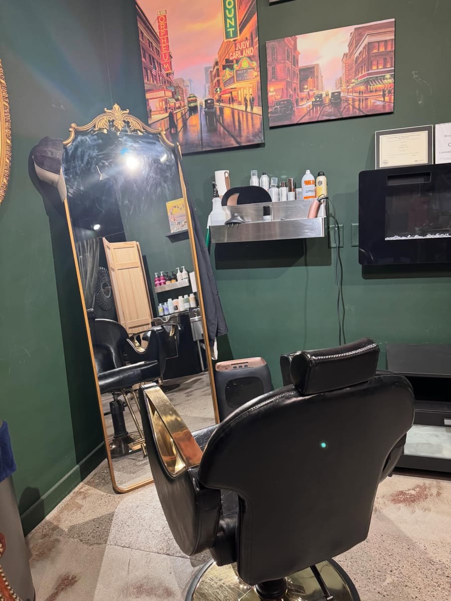 The salon at Dark Horse Brew — a styling chair before a gilded mirror on deep green walls